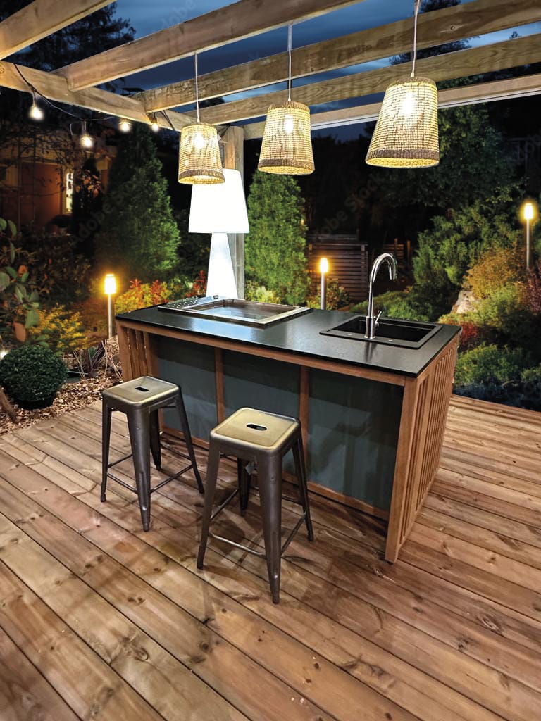 Cuisine d'été éclairée sur une terrasse en bois la nuit.