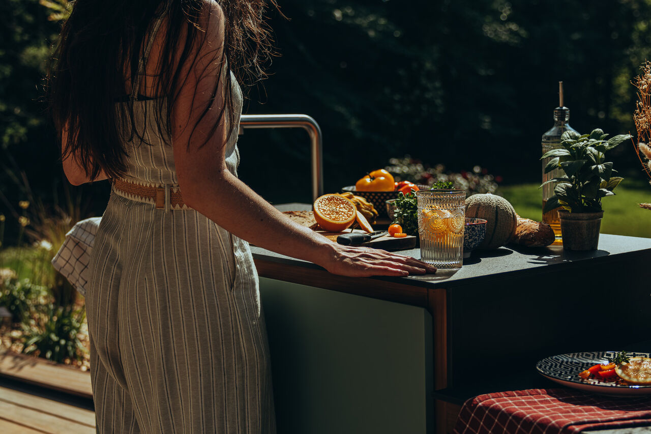 cuisine-l-essentiel-12 Femme préparant un repas frais dans une cuisine d'extérieur.