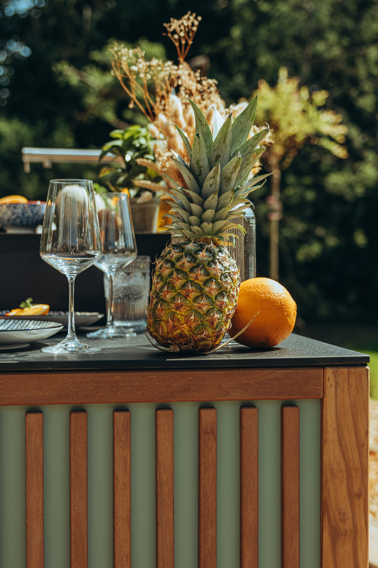 Bar d'été extérieur avec ananas, orange et verres à vin.
