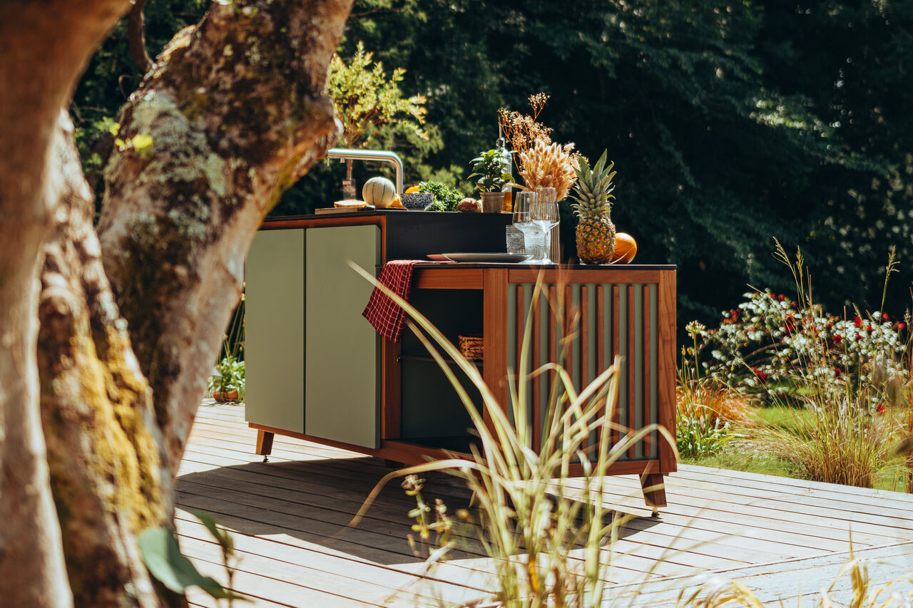 cuisine-l-essentiel-19 Cuisine d'extérieur moderne sur une terrasse en bois ensoleillée.