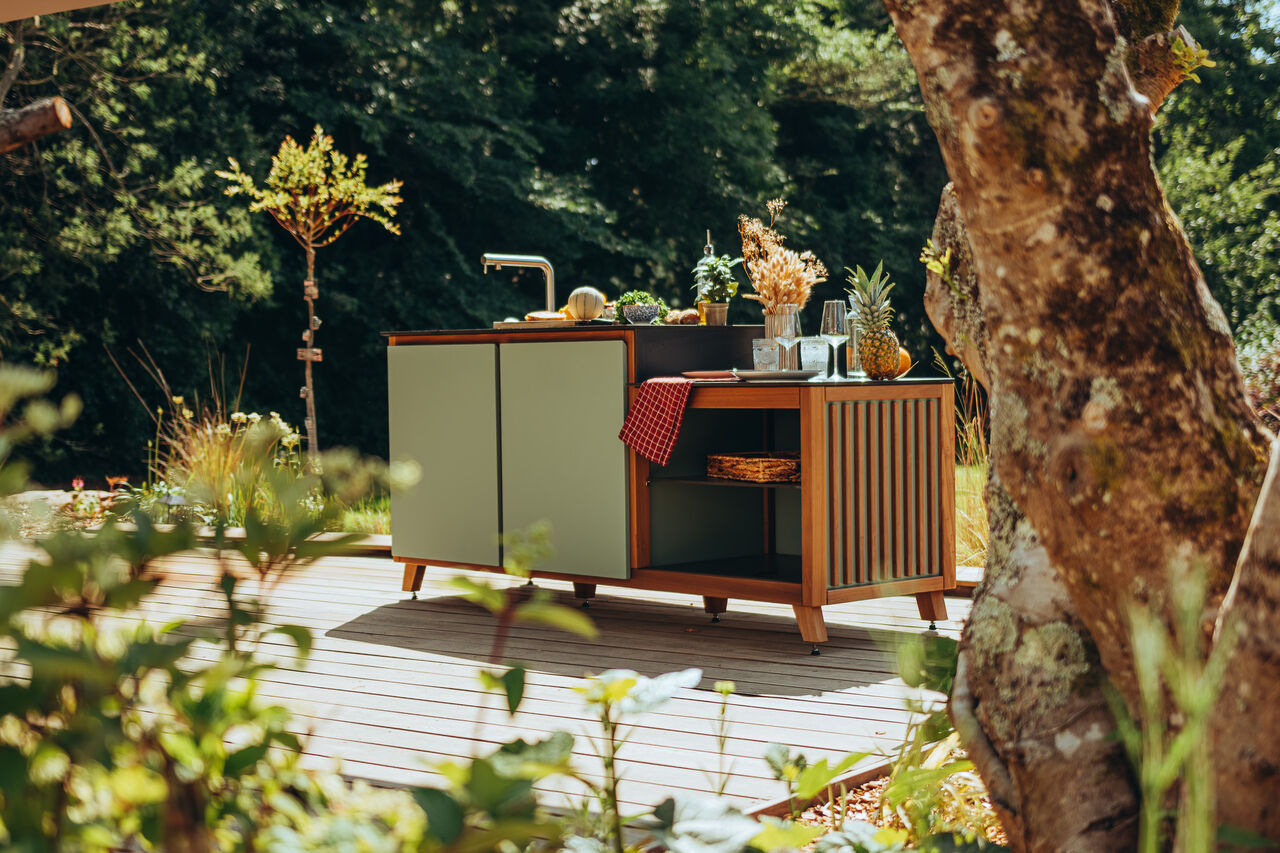 Cuisine d'extérieur design sur une terrasse en bois ensoleillée.
