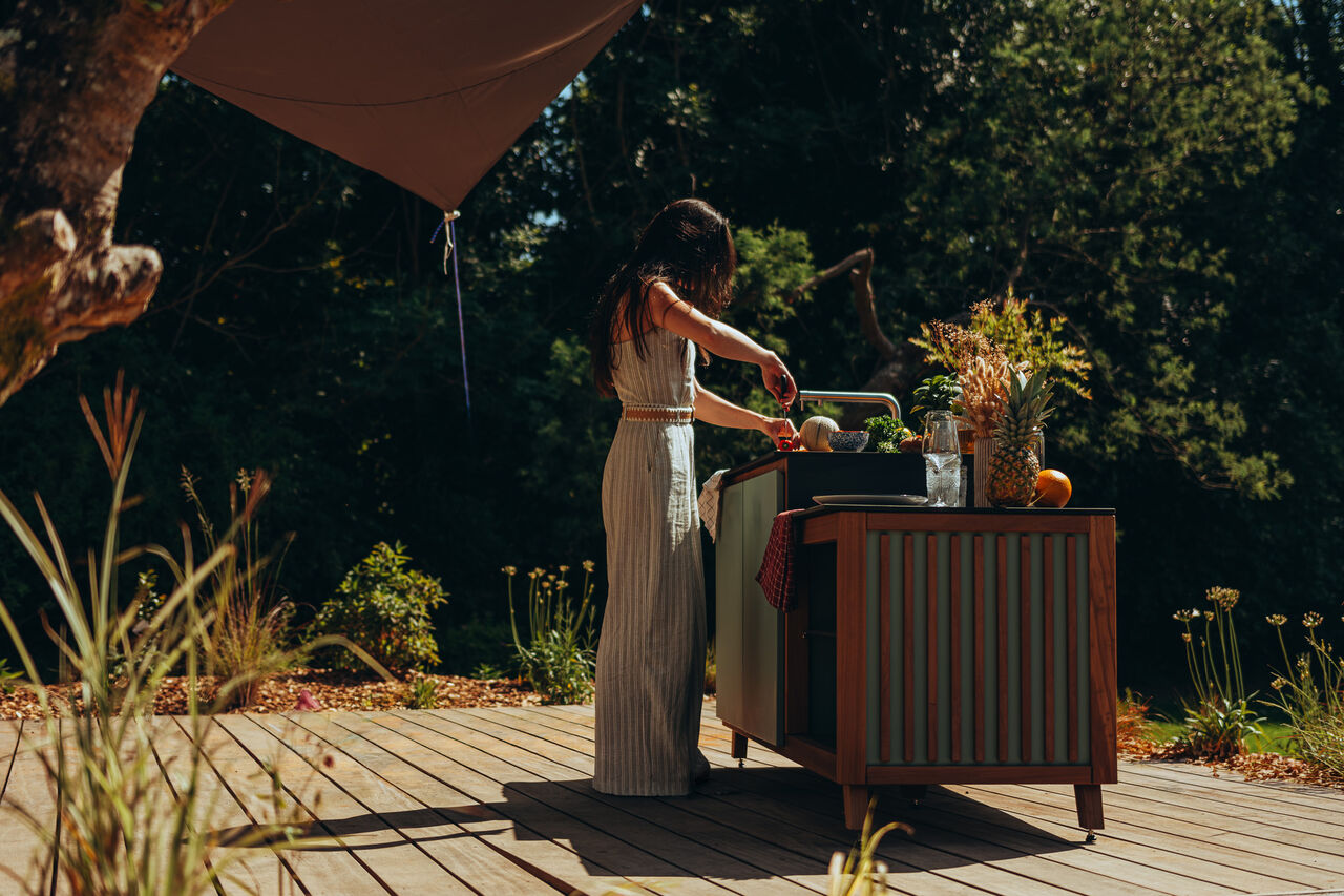 Femme préparant des fruits sur une terrasse en bois.