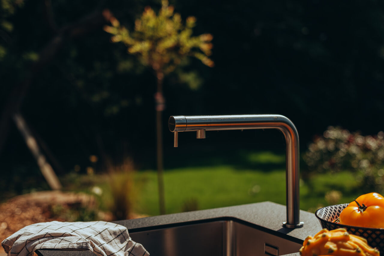 Robinet moderne en acier inoxydable dans une cuisine extérieure.