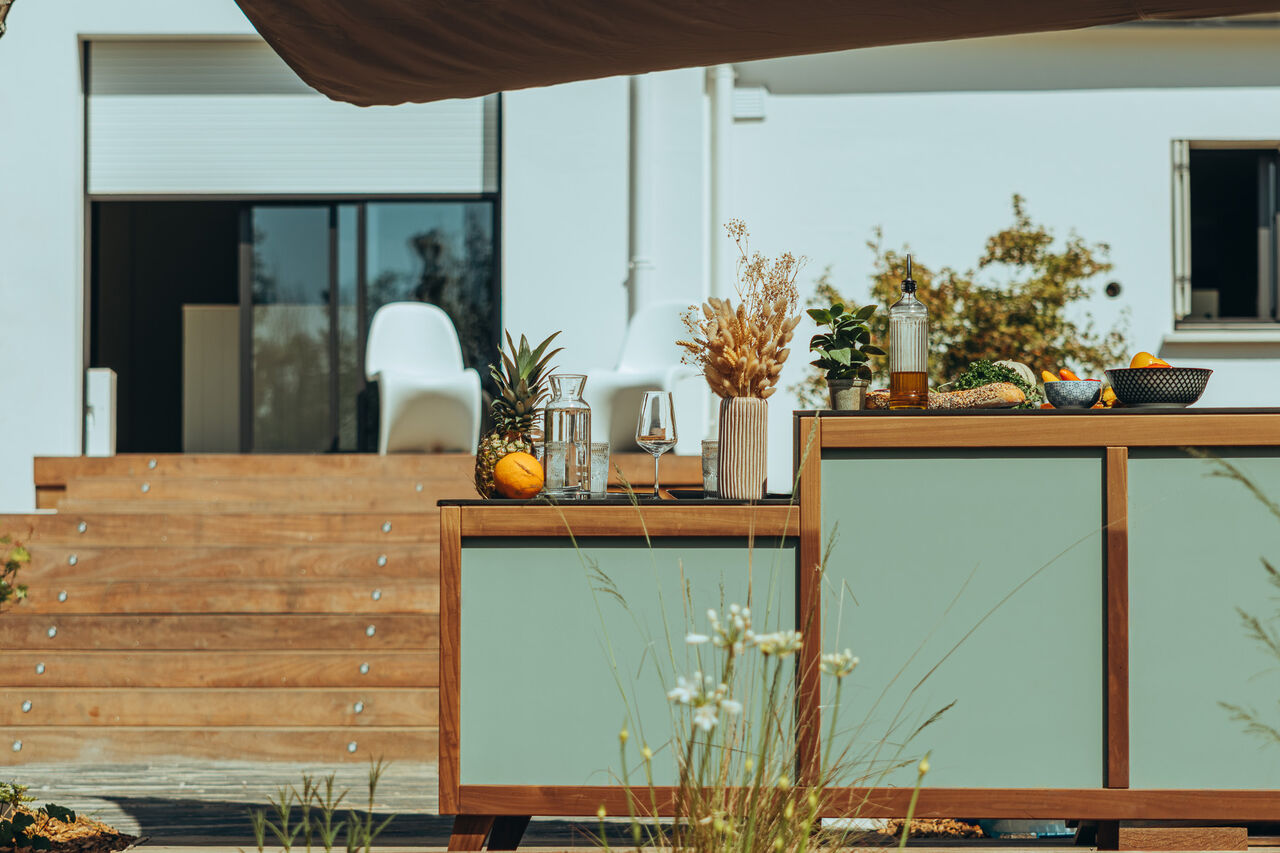 Cuisine d'extérieur moderne avec bar vert sauge et terrasse bois.