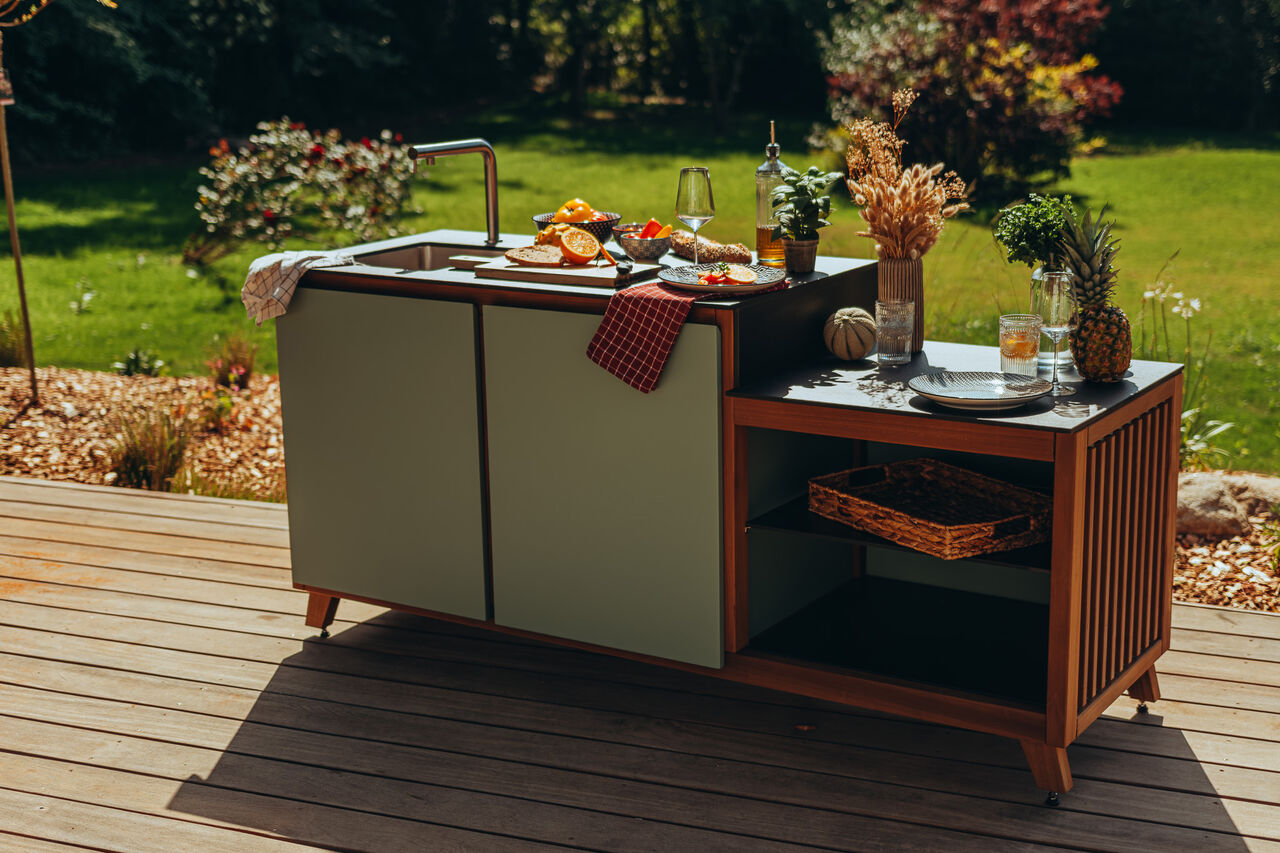 Cuisine extérieure moderne avec évier sur une terrasse boisée.