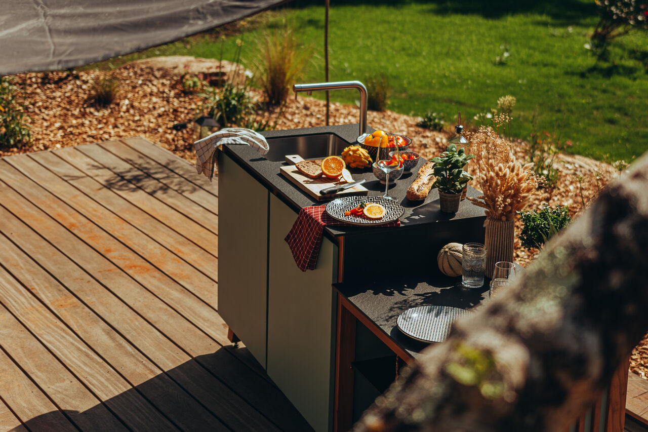 Cuisine d'extérieur moderne avec évier sur une terrasse en bois.